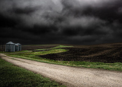 Grain Bins in the middle of an open field against a dark sky