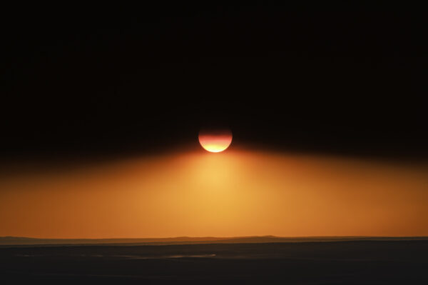 Sun dipping below the canopy of wildfire smoke at sunset